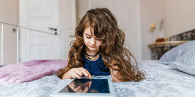 Dziewczynka przeglądająca tablet na łóżku w pokoju